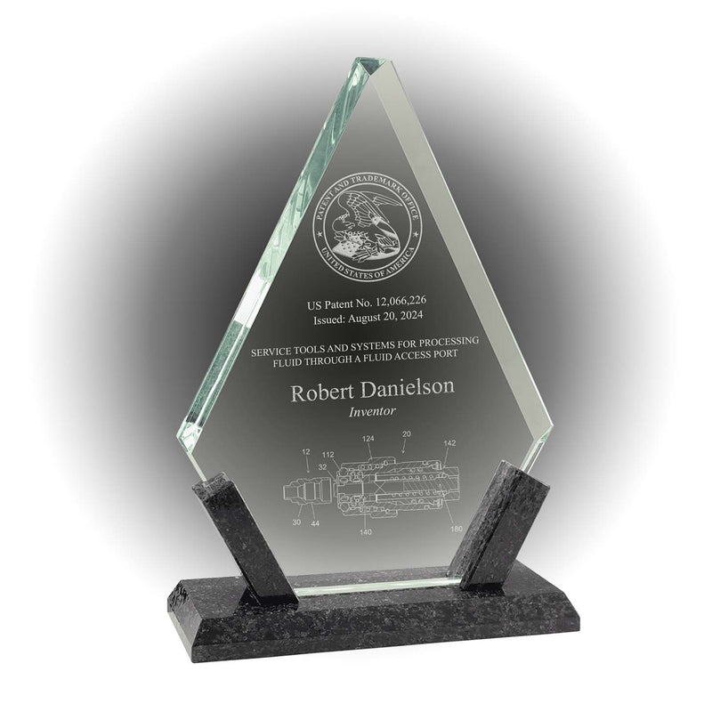 Angled clear glass patent and inventor award on black marble base, engraved with USPTO seal and patent illustration